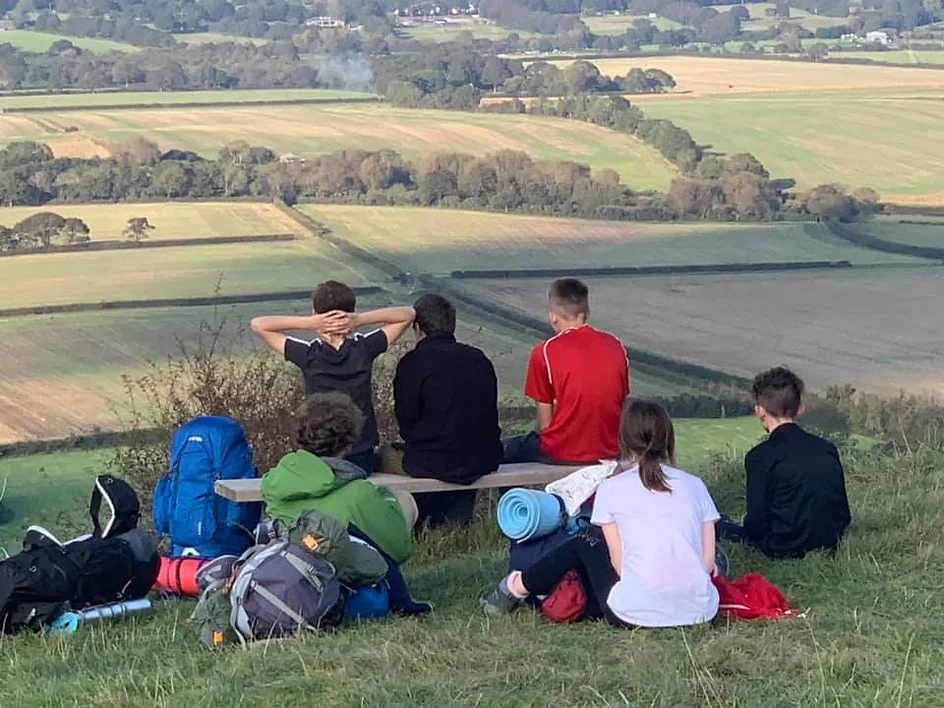 Students sat on a grassy area looking over a valley