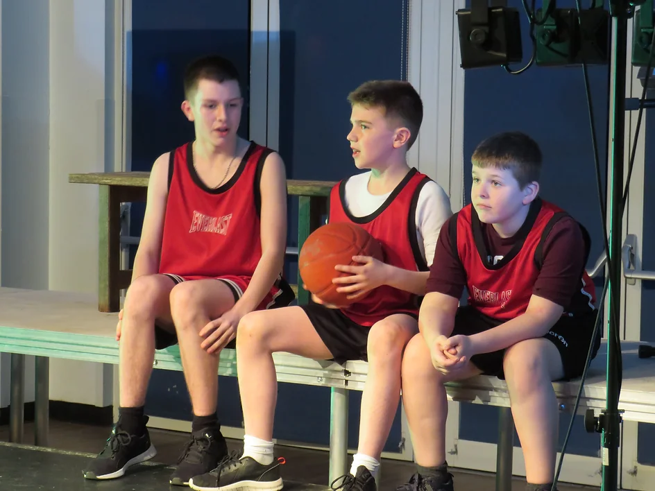 Students sitting on a bench with a basketball