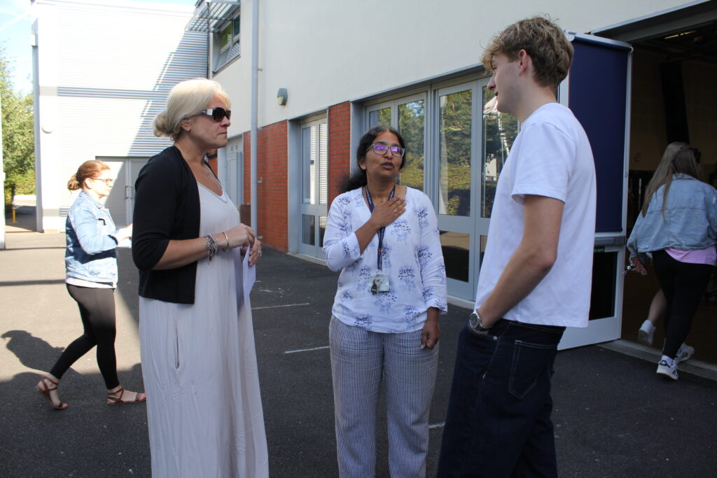 A male Post-16 student is pictured speaking to two female members of staff, after having just received his A-Level results.