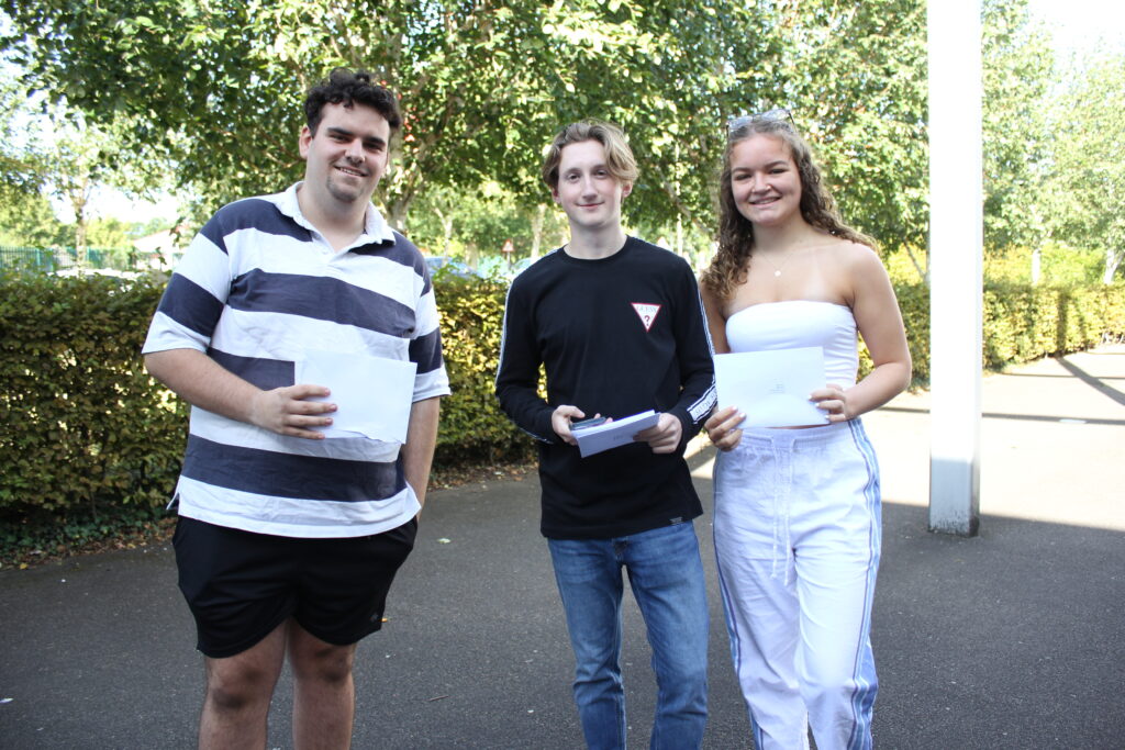 Three Post-16 students, two male and one female, are pictured smiling for the camera, whilst holding up their A-Level results.