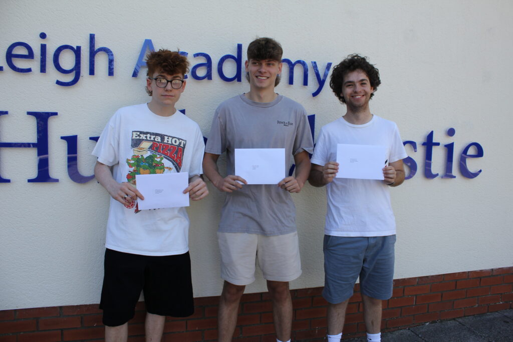 Three male Post-16 students are pictured smiling for the camera together outdoors, after having just opened their A-Level results.